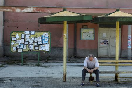 Death notices are seen on a notice board as a man sits at a bus station in the village of Kalna, near the south-eastern town of Knjazevac, Serbia, August 16, 2016. REUTERS/Marko Djurica