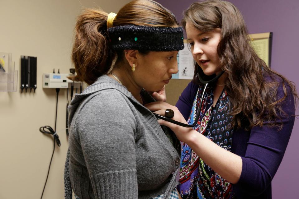 FILE - In this March 28, 2013 file photo, medical resident Stephanie Place examines Maria Cazho at the Erie Family Health Center in Chicago.