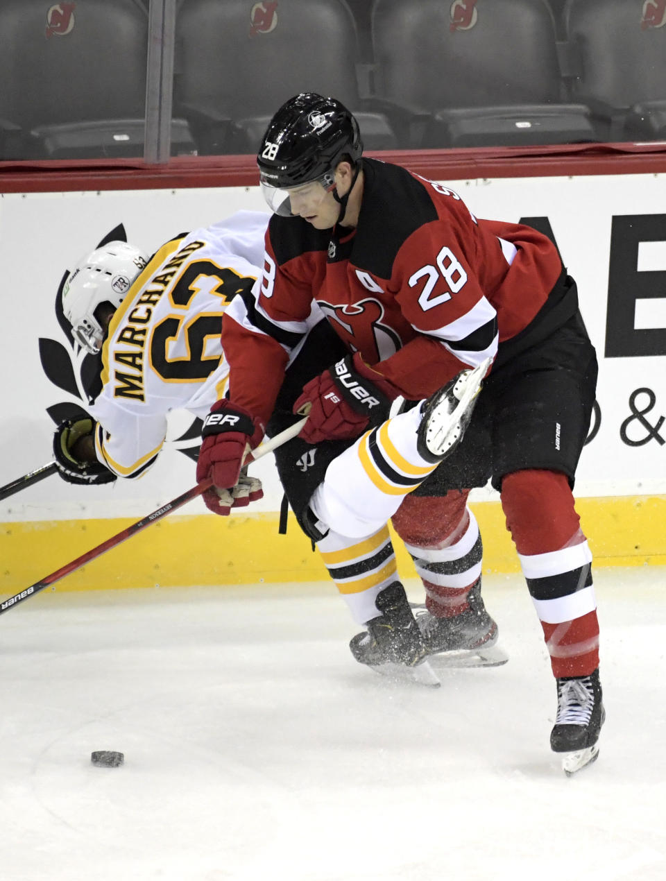 New Jersey Devils defenseman Damon Severson (28) checks Boston Bruins center Brad Marchand (63) during the first period of an NHL hockey game Thursday, Jan. 14, 2021, in Newark, N.J. (AP Photo/Bill Kostroun)