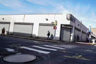 Pedestrians pass shuttered storefronts on Thursday, Oct. 15, 2020, as restrictions are imposed due to a COVID-19 infection rate increase in the Far Rockaway neighborhood of the borough of Queens in New York. After shutdowns swept entire nations during the first surge of the coronavirus earlier this year, some countries and U.S. states are trying more targeted measures as cases rise again around the world. (AP Photo/John Minchillo)