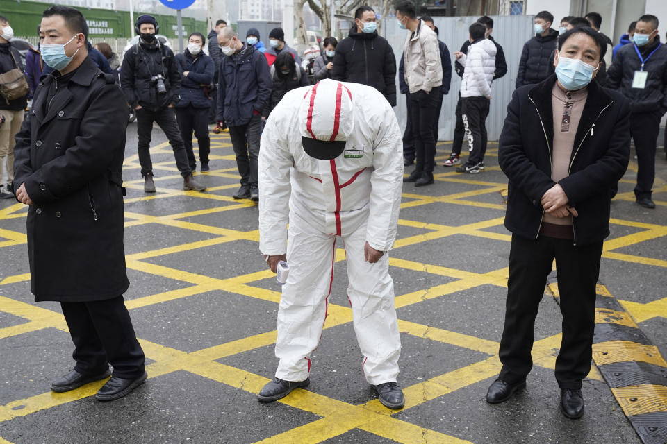 A tired worker in protective overalls bends over to stretch at the entrance of the Hubei Center for Disease Control and Prevention as the World Health Organization team makes a field visit in Wuhan in central China's Hubei province on Monday, Feb. 1, 2021. (AP Photo/Ng Han Guan)