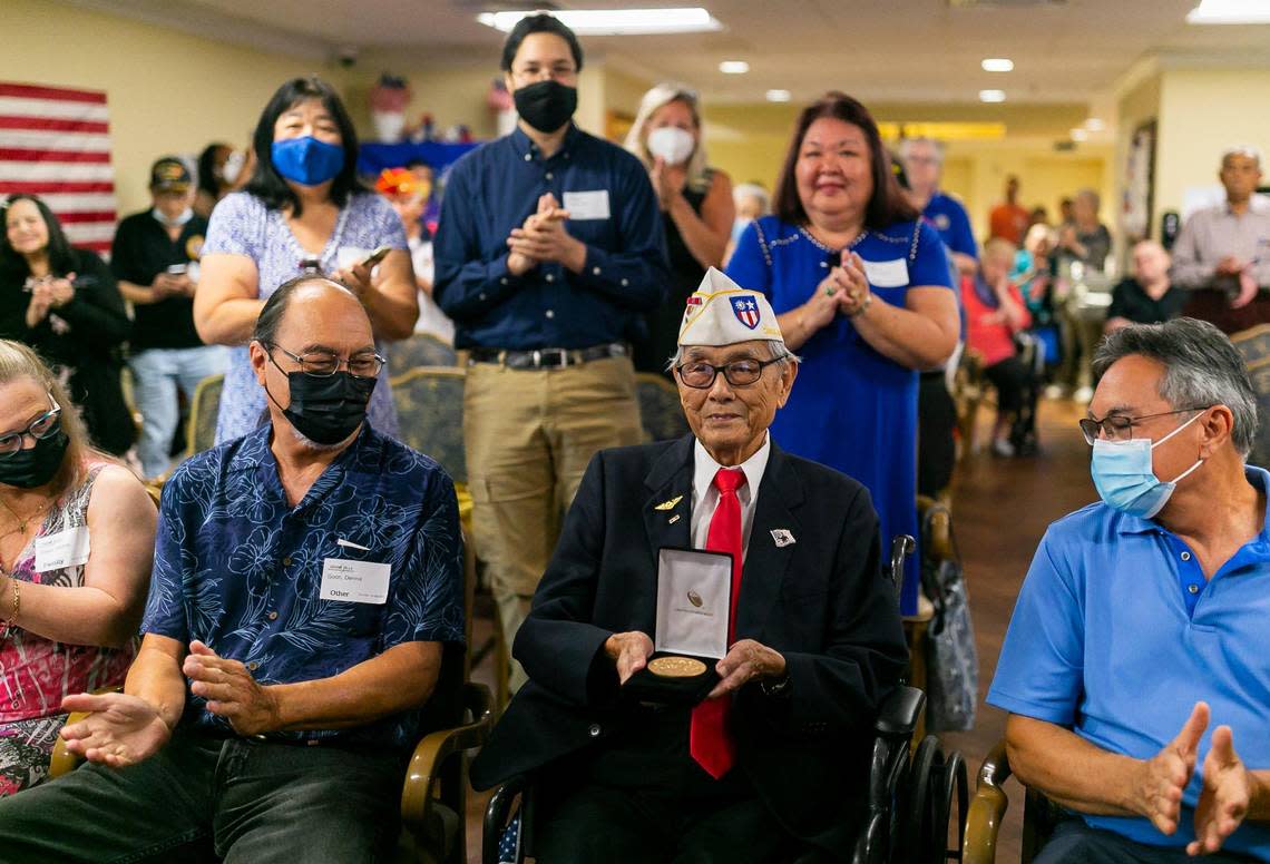 U.S. Army veteran Richard Goon, 98, center, is congratulated while holding the Congressional Gold Medal during a virtual ceremony at the Grand Villa Senior Living Community on Tuesday, July 5, 2022, in Deerfield Beach, Fla. During his service, Goon trained as a cryptographer and eventually was stationed along the Chinese and Indochina border where he helped train the Chinese army to fight the Japanese forces.