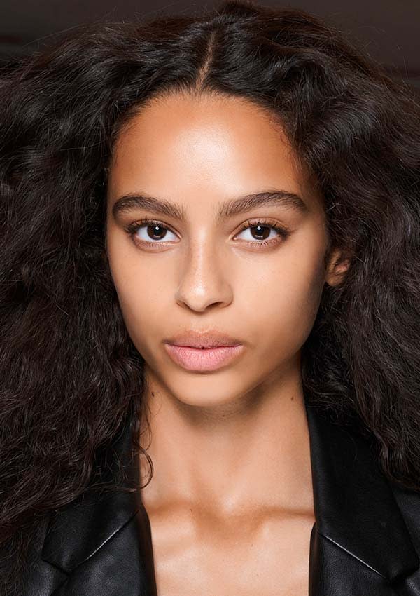 Modelo en el backstage del desfile de primavera-verano 2022 de Balmain, con una melena morena y sana