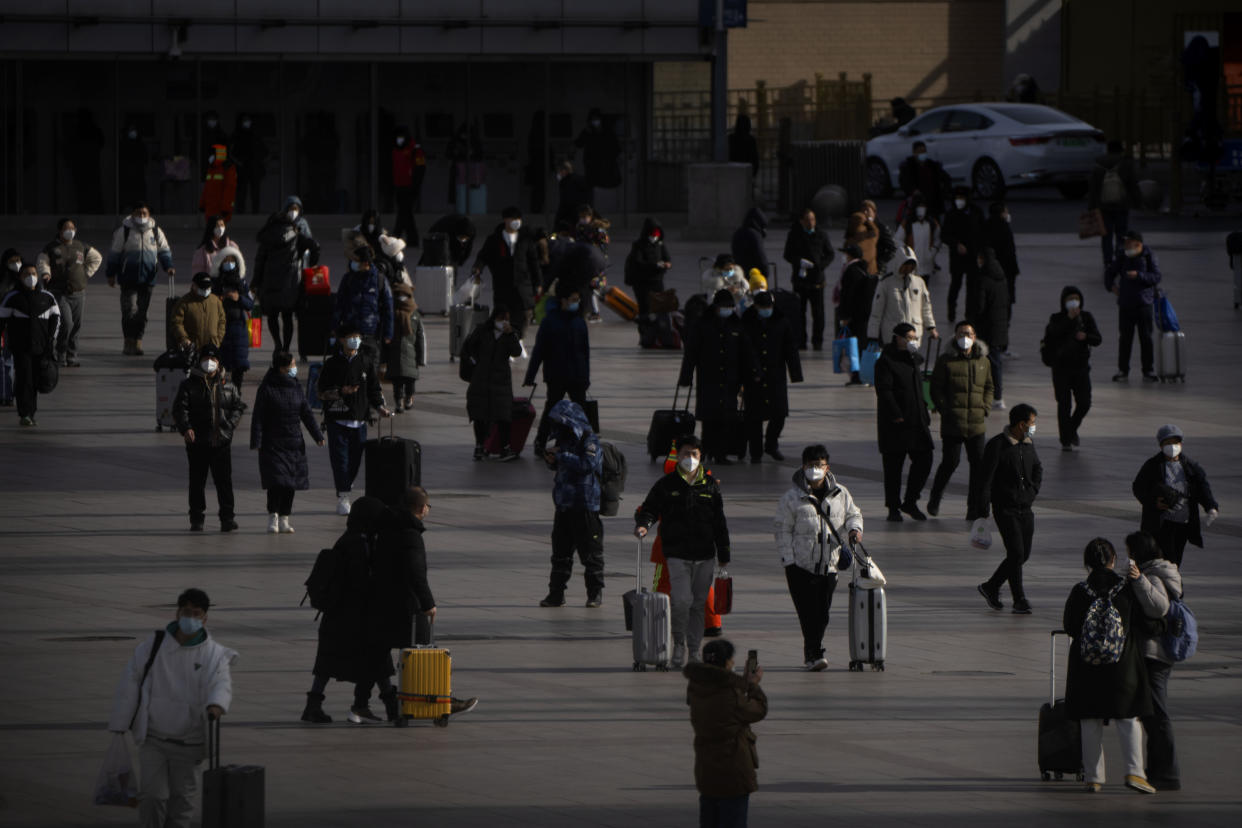 Travelers wearing face masks walk toward the entrance of the Beijing Railway Station in Beijing, Saturday, Jan. 14, 2023. Millions of Chinese are expected to travel during the Lunar New Year holiday period this year. (AP Photo/Mark Schiefelbein)