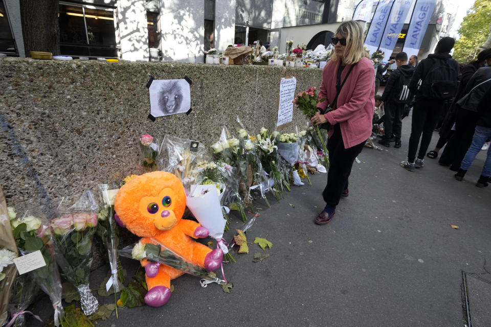 A woman lays flowers outside the building where the body of 12-year-old schoolgirl was discovered in a trunk, in Paris, Wednesday, Oct. 19, 2022. France has been "profoundly shaken" by the murder of a 12-year-old schoolgirl, whose body was found in a plastic box, dumped in a courtyard of a building in northeastern Paris, the government spokesman Olivier Veran said on Wednesday. (AP Photo/Michel Euler)