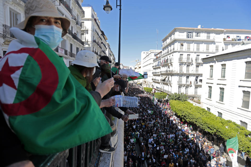 FILE - In this March 12, 2021 file photo, demonstrators watch a crowd marching in Algiers. Two years after it ousted Algeria’s long-serving leader, the country’s pro-democracy movement is at a crossroads. There are fears it’s been infiltrated by a group with links to an Islamist party outlawed during a dark era of strife in the 1990s. (AP Photo/Toufik Doudou, File)