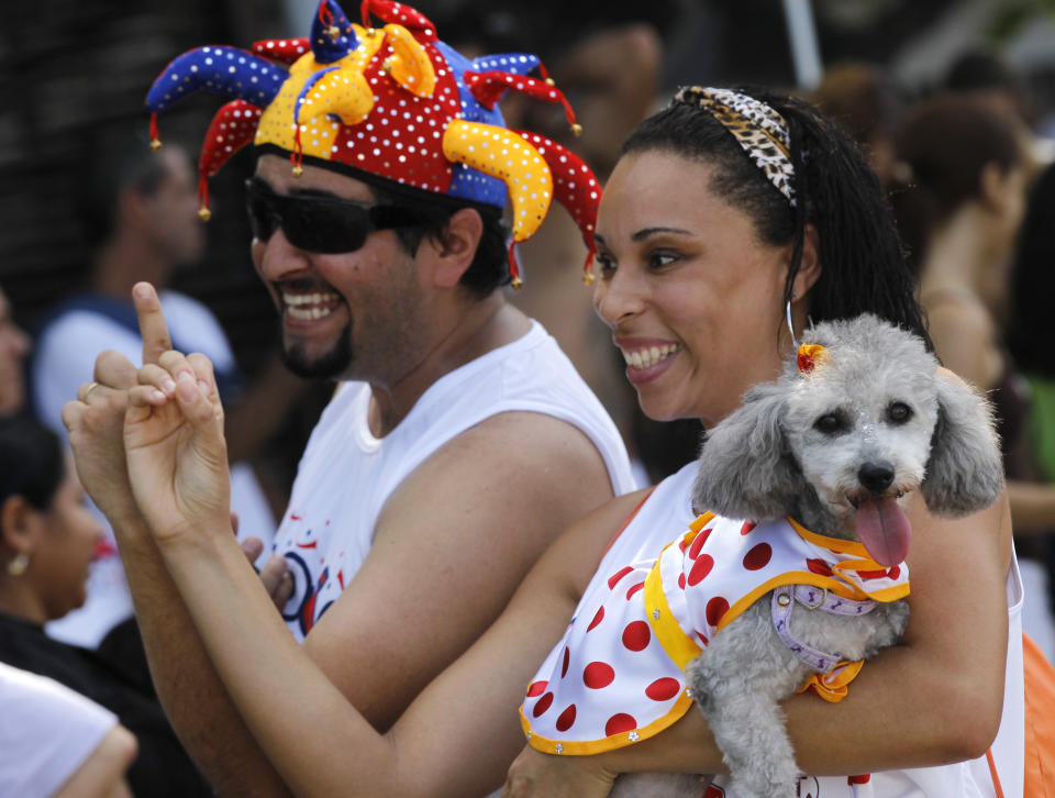 A man and a woman take their dog to the "Blocao" dog carnival parade in Rio de Janeiro, Brazil, Sunday, Feb. 12, 2012. (AP Photo/Silvia Izquierdo)