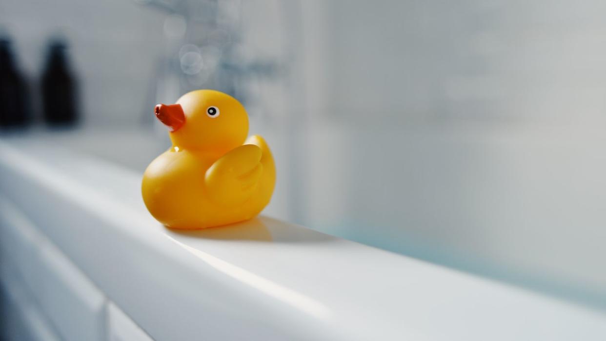 yellow toy rubber duck on side of bath