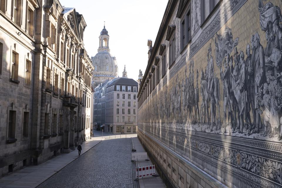 A passer-by walks along the empty Augustusstrasse next to the 'Fuerstenzug' mural in front of the Frauenkirche in Dresden, Germany, Thursday, Dec. 2, 2021. Germany's outgoing Chancellor Angela Merkel and her likely successor met with state governors to consider tighter rules to curb coronavirus infections. The rise in COVID-19 cases over the past weeks and the arrival of the new omicron variant have prompted warnings from scientists and doctors that medical services in the country could become overstretched in the coming weeks unless drastic action is taken. Photo: Sebastian Kahnert/dpa via AP)