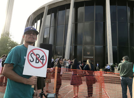 FILE PHOTO: A protester against the Texas state law to punish "sanctuary cities" stands outside the U.S. Federal court in San Antonio, Texas, U.S., June 26, 2017. REUTERS/Jon Herskovitz/File Photo