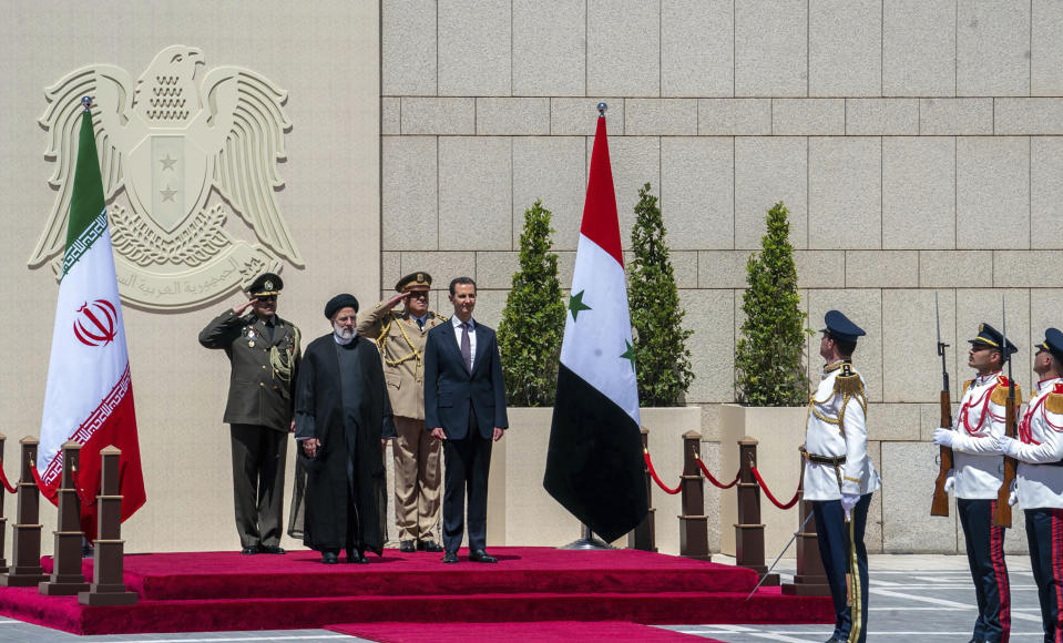 In this photo released by the official Facebook page of the Syrian Presidency, Syrian President Bashar Assad and Iranian President Ebrahim Raisi review an honor guard during a welcome ceremony upon Raisi's arrival in Damascus, Syria, Wednesday, May 3, 2023. Iranian President Raisi Wednesday met Syrian President Assad in Damascus in a bid to boost cooperation between the two allies, state media reported. (Syrian Presidency via Facebook via AP)