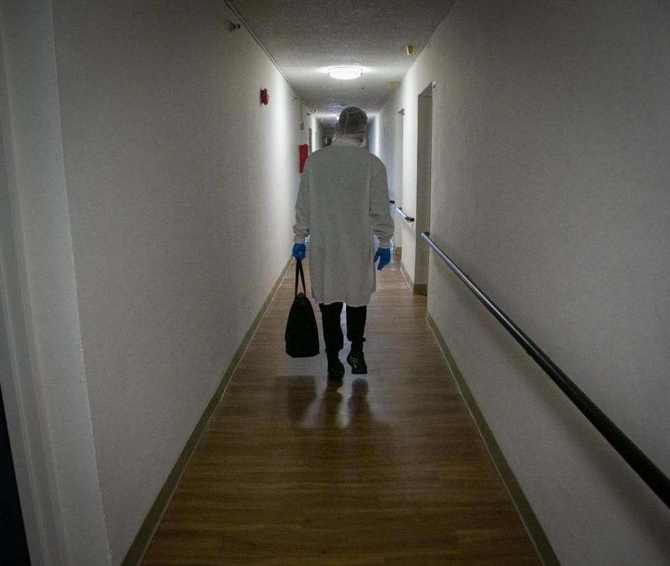 Yuri Kuzenkov of DeliverLean carries a bag containing meals down the hallway to a client’s apartment on Jan. 7, 2021. The company delivers about 18,000 meals a day in the county program.
