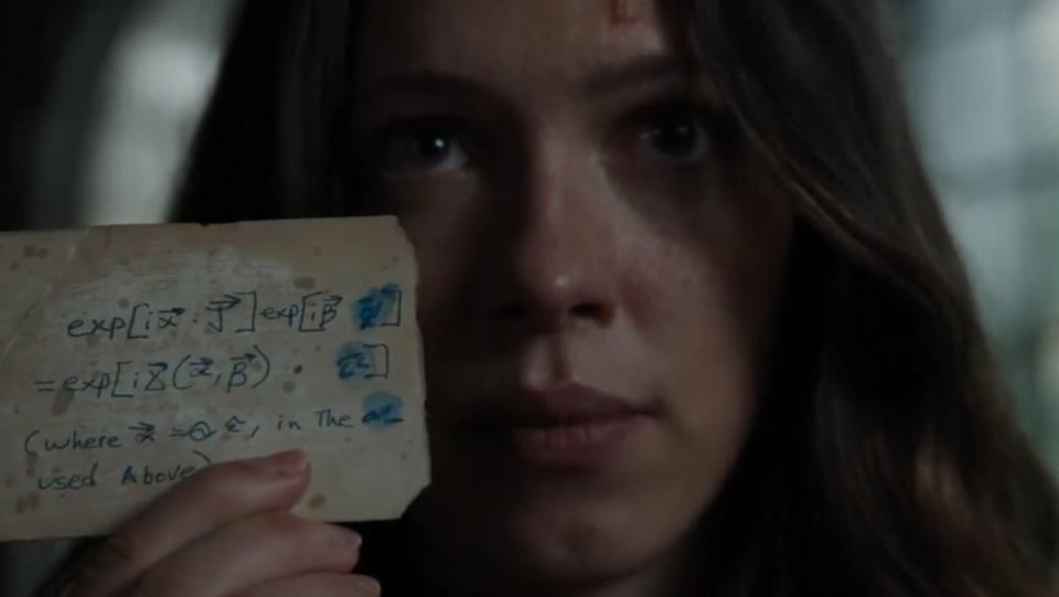 A woman holds up a small card with a complicated formula on it in Iron Man 3