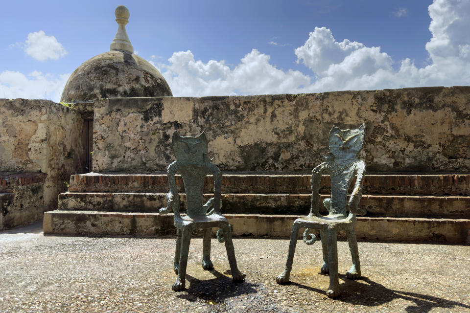 Chairs in the figure of cats sit in Old San Juan, Puerto Rico, Thursday, Nov. 3, 2022. Cats have long strolled through the cobblestone streets of the historic district and are so beloved they even have their own statues in Old San Juan. (AP Photo/Alejandro Granadillo)