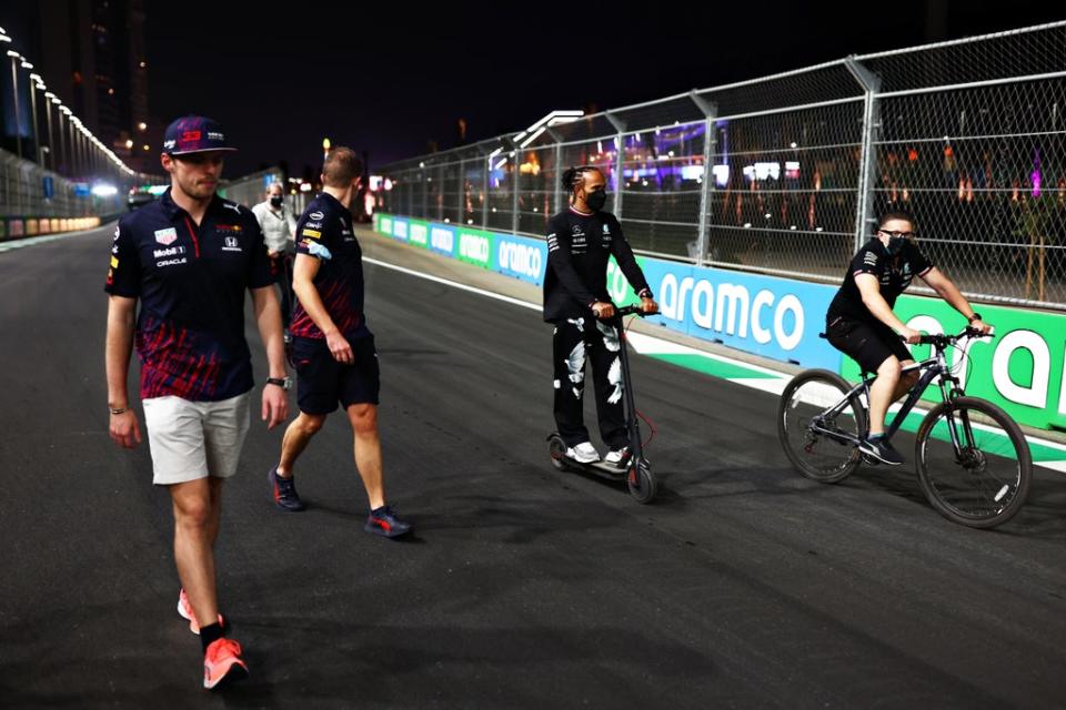 Max Verstappen, left, and Lewis Hamilton, centre, walk (or ride) the track (Getty Images)