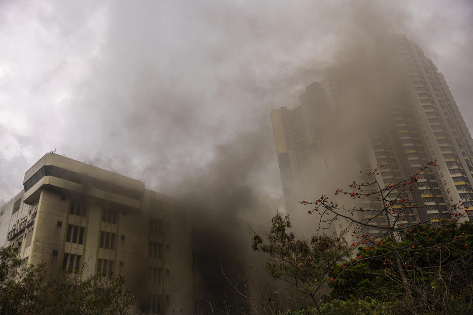 Smoke billows from a warehouse, left, in Cheung Sha Wan, a residential and industrial area, in Hong Kong, Friday, March 24, 2023. Hong Kong firefighters were battling a blaze Friday at a warehouse that forced more than 3,000 people to evacuate, including students, police said.(AP Photo/Louise Delmotte)