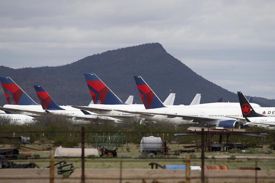 In this Wednesday, March 18, 2020 photo, Delta Air Lines airplanes sit parked next to one another at Pinal Airpark, in Red Rock, Ariz., as many passenger planes are being kept at the facility while airlines cut back on service due to the coronavirus. (AP Photo/Ross D. Franklin)