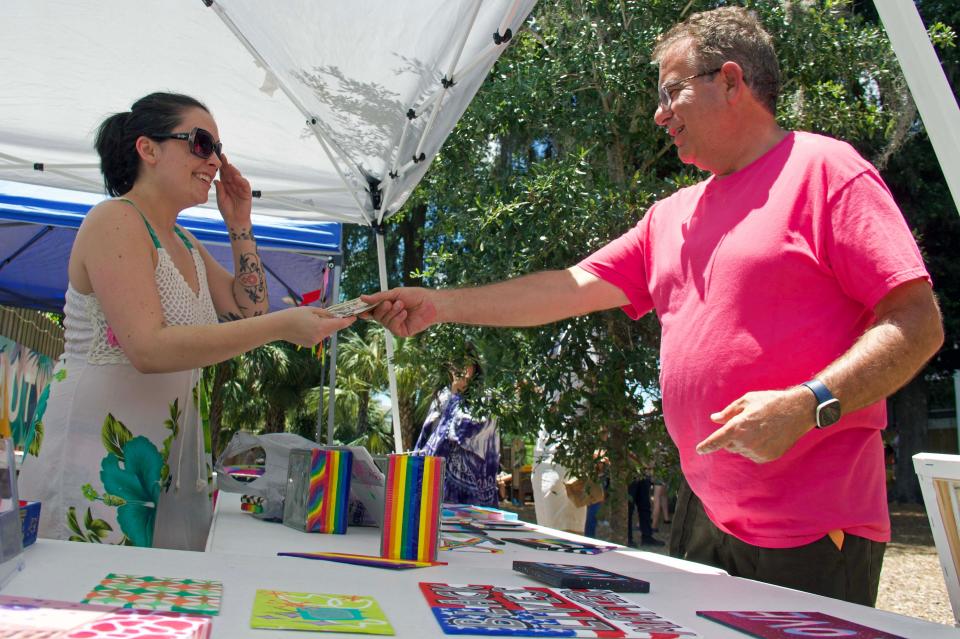 Anne Bottcher, left, owner of ANNESxARTES, makes a sale to Paul Basler at 4th Ave Food Park’s Queer Maker’s Market in Gainesville on Saturday.
