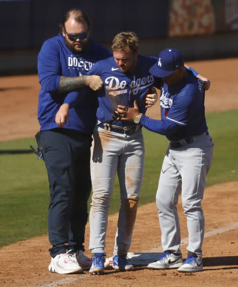 Dodgers' Gavin Lux is loaded onto a cart with the help of a trainer and manager Dave Roberts after getting injured.