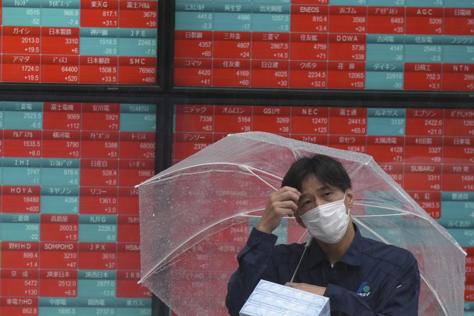 A person stands in the rain in front of an electronic stock board showing Japan's Nikkei 225 index at a securities firm Tuesday, June 18, 2024, in Tokyo. Shares were mostly higher in Asia on Tuesday after U.S. stocks rallied to more records, with gains for technology companies pushing the benchmarks higher. (AP Photo/Eugene Hoshiko)