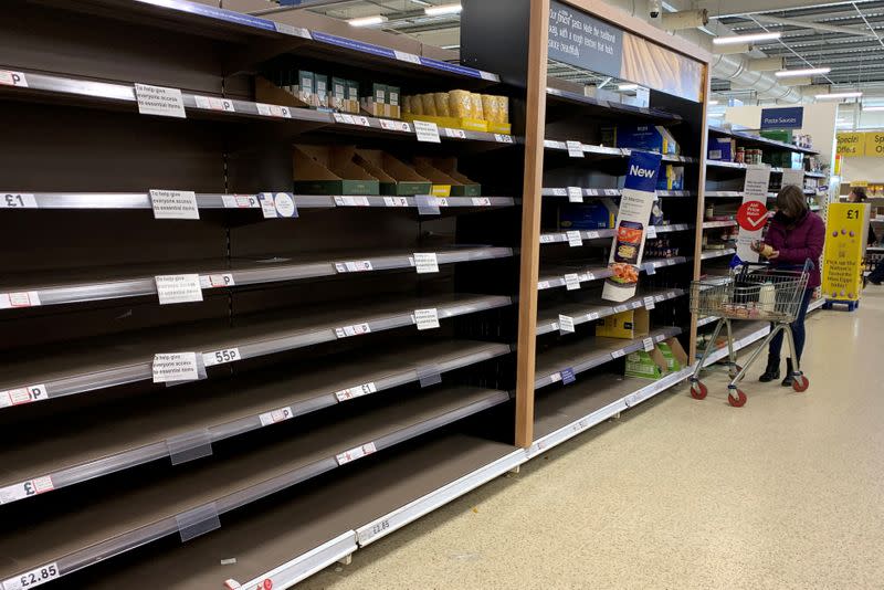 FILE PHOTO: A woman pushes her trolley along the empty pasta aisle inside a Tesco supermarket amid the coronavirus disease (COVID-19) outbreak in Manchester