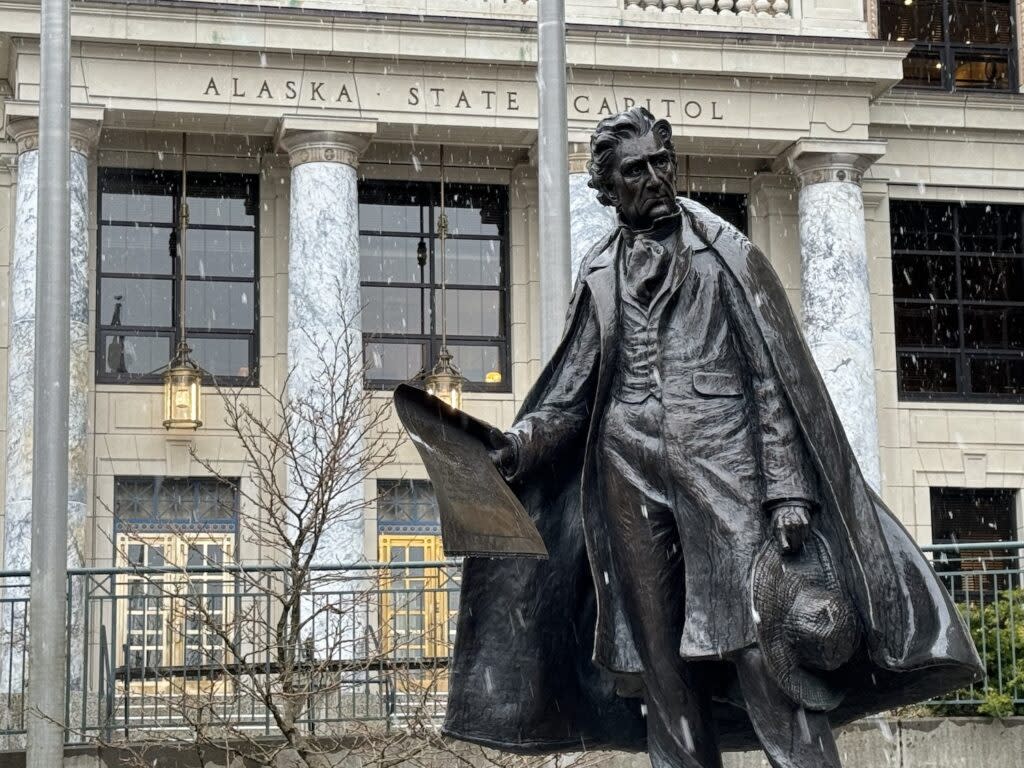 Snow falls on the Alaska Capitol and the statue of William Henry Seward on Monday, April 1, 2024. (Photo by James Brooks/Alaska Beacon)