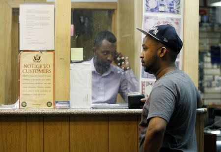 Mohammed Ahamed (R) waits as Shakir Hussein, owner of money transfer business Mustaqbal Express in Minneapolis, wires money to his ex-wife in Somalia, June 23, 2014. REUTERS/Eric Miller