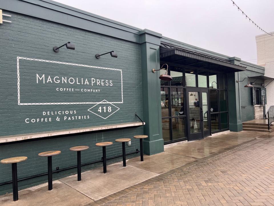 A photo of a deep green restaurant with "Magnolia Press" written on the side of it.