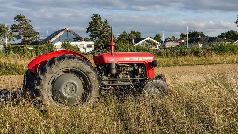 A photo of an old red tractor in a field of grass. 