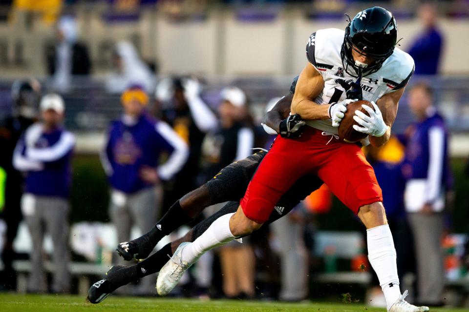 Cincinnati Bearcats wide receiver Alec Pierce (12) catches a pass as East Carolina Pirates cornerback Ja'Quan McMillian (21) tackles him in the first half of the NCAA football game between the Cincinnati Bearcats and the East Carolina Pirates at Dowdy-Ficklen Stadium in Greenville, NC, on Friday, Nov. 26, 2021.