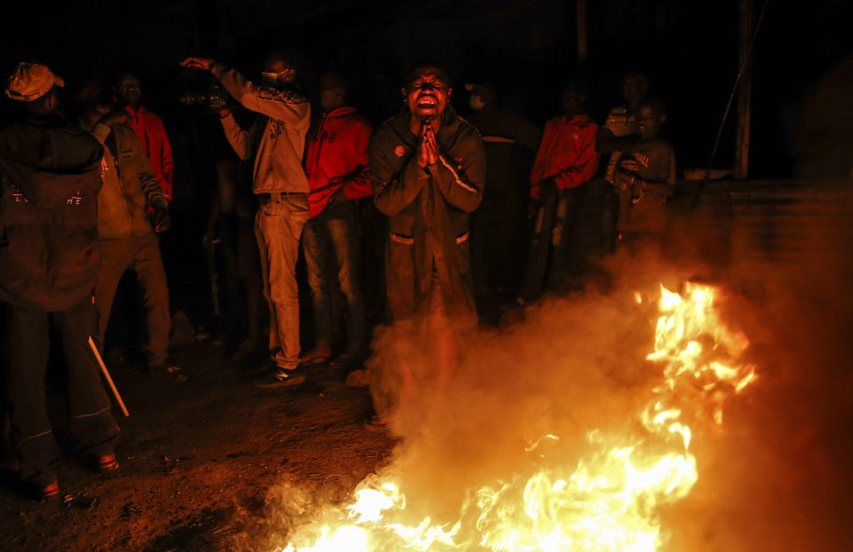 In this photo taken Monday, June 1, 2020, residents burn fires late at night on a street to protest the death of James Mureithi, a homeless man who protesters alleged was shot dead by police during the nightly dusk-to-dawn curfew established to curb the spread of the coronavirus, in the Mathare slum, or informal settlement, of Nairobi, Kenya. Hundreds of people in Mathare left their homes and burnt tires on the streets in the latest outrage over alleged police brutality, with a rights activist claiming that 19 Kenyans from low-income neighborhood have died from police actions in enforcing the curfew. (AP Photo/Brian Inganga)