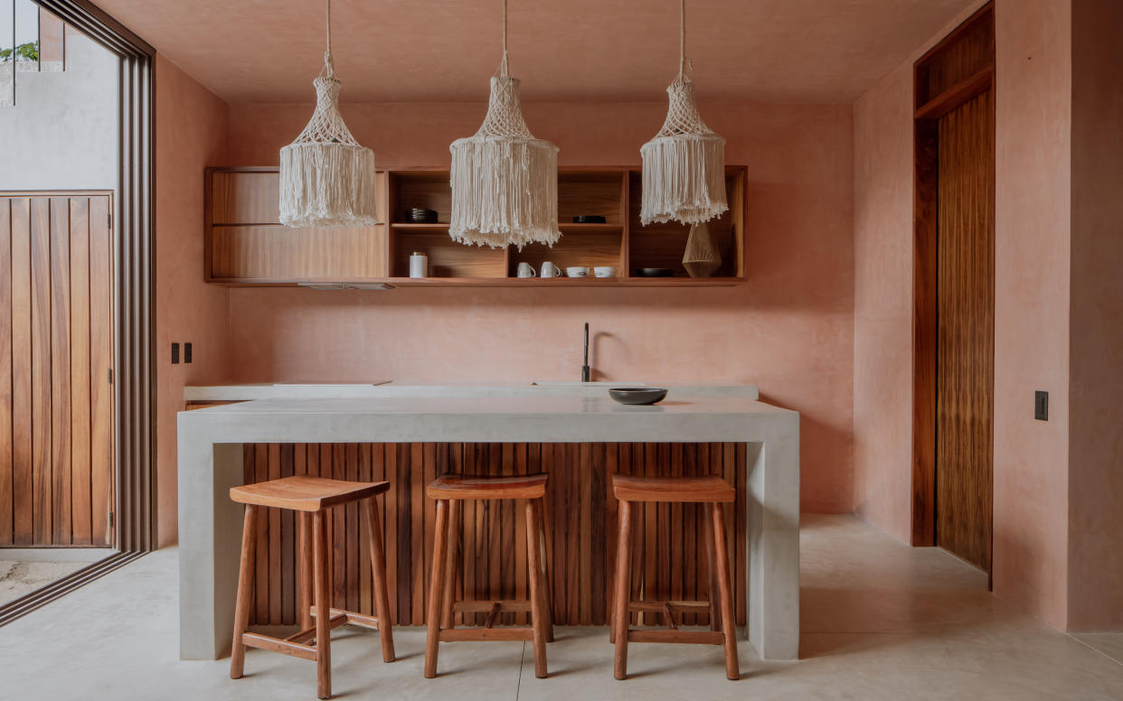  A kitchen with salmon pink walls and a beige lighting piece. 