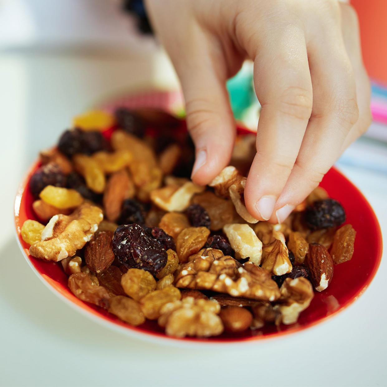 womans hand reaching for dried fruits and nuts