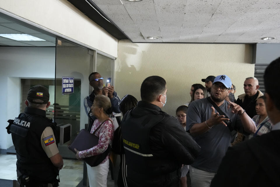 Personas aguardan para entrar a la embajada de Venezuela mientras la policía hace guardia en Quito, Ecuador, el martes 16 de abril de 2024. El presidente venezolano, Nicolás Maduro, ordenó el cierre de la embajada y de los consulados de su país en Ecuador en solidaridad con México y como rechazo a la irrupción de la policía ecuatoriana en la embajada de México en Quito. (AP Foto/Dolores Ochoa)