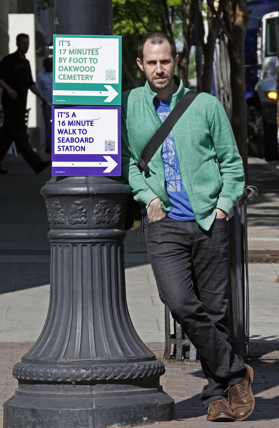 CORRECTS SPELLING OF TOMASULO - Matt Tomasulo poses for a photo by some of his signs in downtown Raleigh, N.C., Wednesday, April 11, 2012. On a January night he and friends put up 27 signs that advised people how to walk to various locations. The project, part of his master's thesis, has taken off with city officials, with two other states now planning to use his signs. (AP Photo/Gerry Broome)