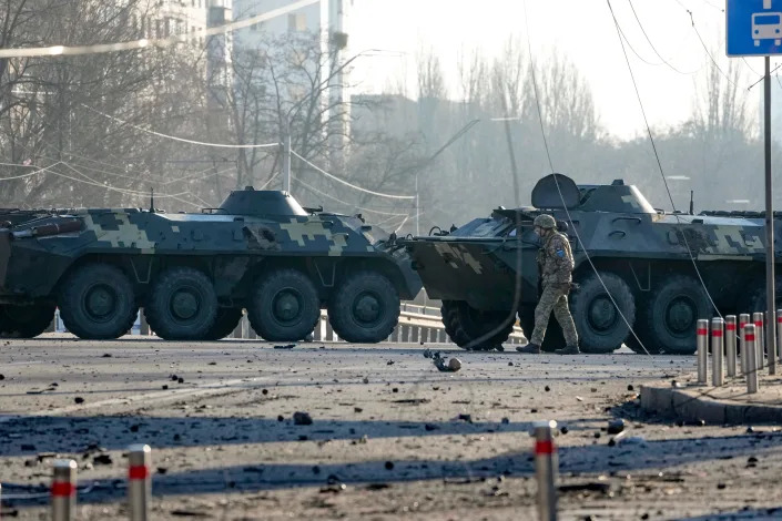 A soldier walks along Ukrainian armored vehicles blocking a street in Kyiv, Ukraine, Saturday, Feb. 26, 2022. Russian troops stormed toward Ukraine&#39;s capital Saturday, and street fighting broke out as city officials urged residents to take shelter.