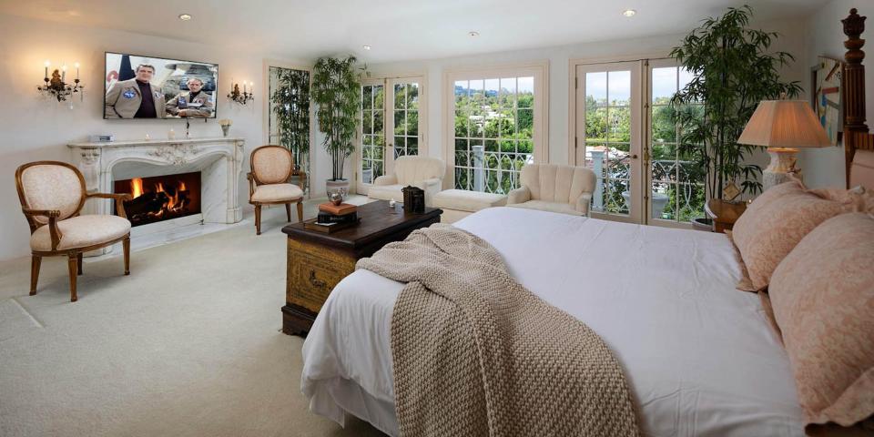 a bed surrounded by seats in front of a fireplace and TV