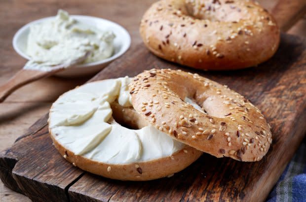 Bagel with cream cheese on wooden table<p>iStock</p>