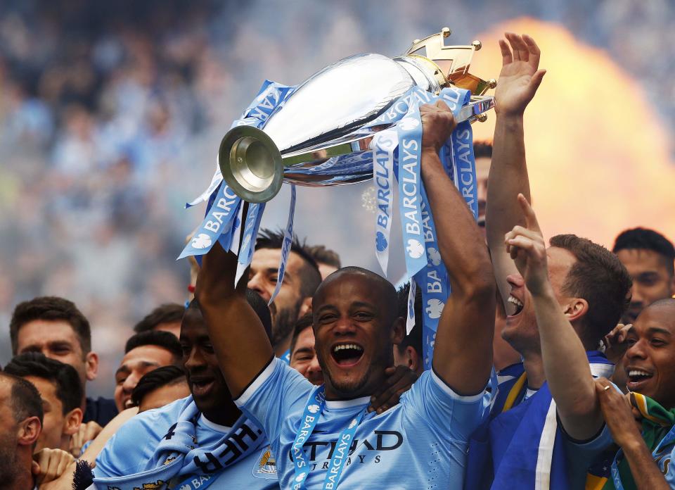 Manchester City's captain Vincent Kompany (C) celebrates with the English Premier League trophy following their soccer match against West Ham United at the Etihad Stadium in Manchester, northern England May 11, 2014. REUTERS/Darren Staples (BRITAIN - Tags: SPORT SOCCER TPX IMAGES OF THE DAY) FOR EDITORIAL USE ONLY. NOT FOR SALE FOR MARKETING OR ADVERTISING CAMPAIGNS. NO USE WITH UNAUTHORIZED AUDIO, VIDEO, DATA, FIXTURE LISTS, CLUB/LEAGUE LOGOS OR "LIVE" SERVICES. ONLINE IN-MATCH USE LIMITED TO 45 IMAGES, NO VIDEO EMULATION. NO USE IN BETTING, GAMES OR SINGLE CLUB/LEAGUE/PLAYER PUBLICATIONS