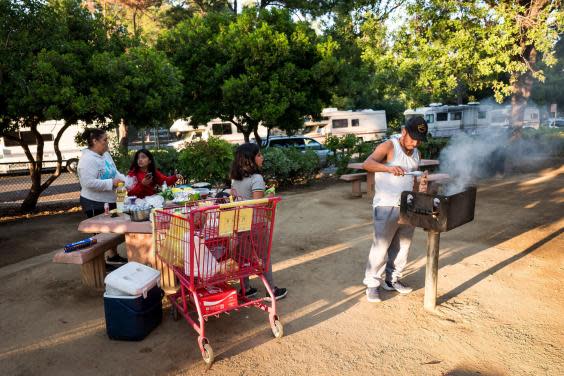 A family cooks dinner in Rengstorff Park across the street from where their RV is parked in Mountain View