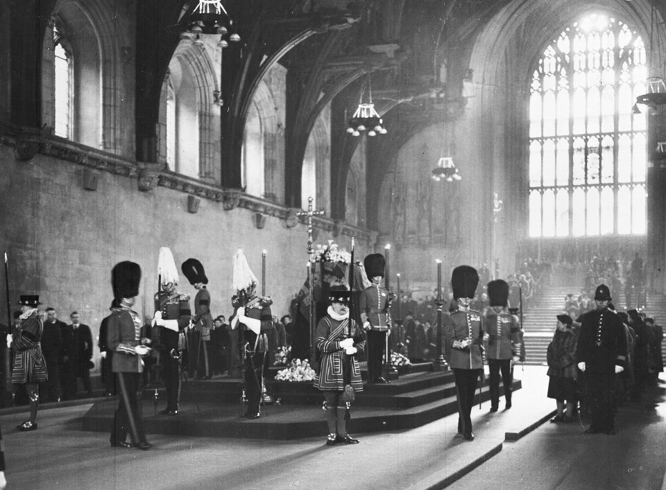 FILE - Members of the public pass the coffin of Britain's King George VI, as it lays in state, and the guard is changed in total silence, in Westminster Hall, London, on Feb. 13, 1952. When Queen Elizabeth II’s grandfather, King George V, died in 1936, life in Britain is unrecognizable to people today. But despite almost a century of change, the images from the queen’s lying in state this week are almost exact copies of those from George V’s time. (AP Photo, File)