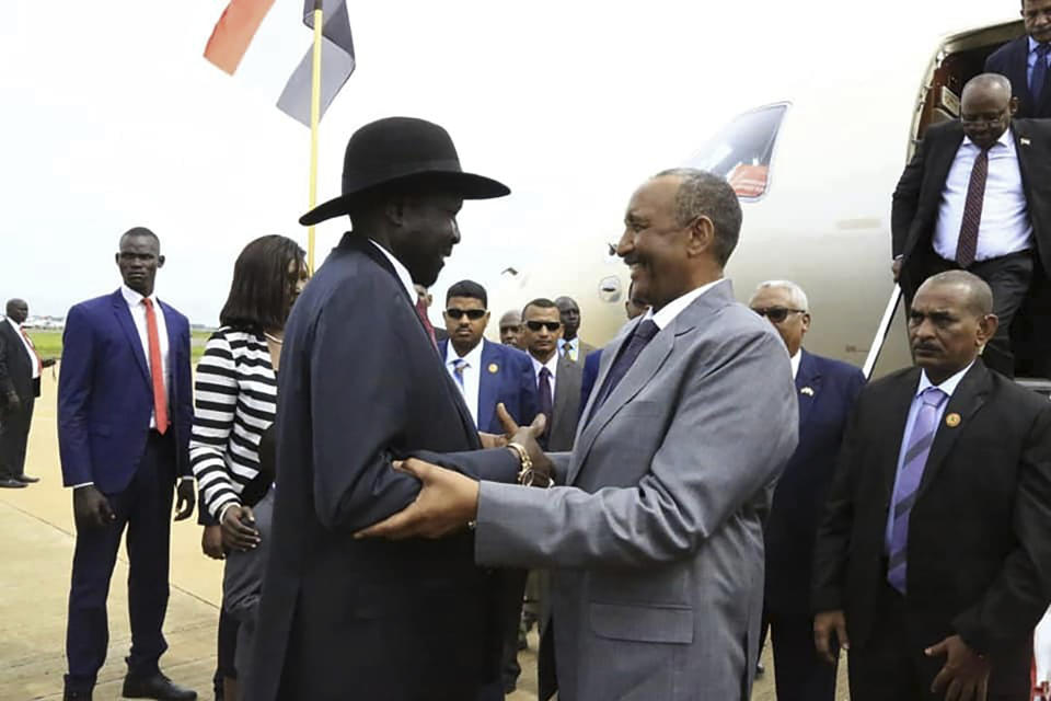 In this photo provided by the official SUNA news agency, Gen. Abdel-Fattah Burhan, center right, head of Sudan’s sovereign council, is greeted by South Sudan’s President Salva Kiir, center left, in Juba, South Sudan, Monday, Oct. 14, 2019. Sudan's new transitional government is starting talks Monday with rebel leaders in South Sudan's capital, Juba to kick off peace talks aimed at ending the country's yearslong civil wars. Achieving peace is crucial to the transitional government in Sudan. It has counted on ending the wars with rebels in order to revive the country's battered economy through slashing the military spending, which takes up much of the national budget. (SUNA via AP)