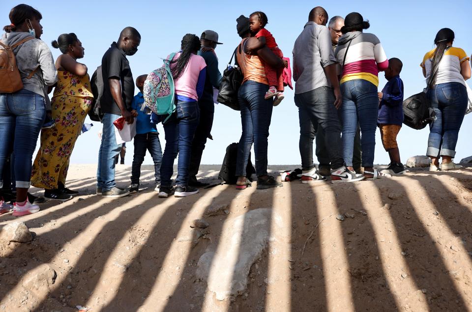 Immigrants from Haiti, who crossed through a gap in the U.S.-Mexico border barrier, wait in line in May to be processed in Yuma, Ariz., in May 2022.