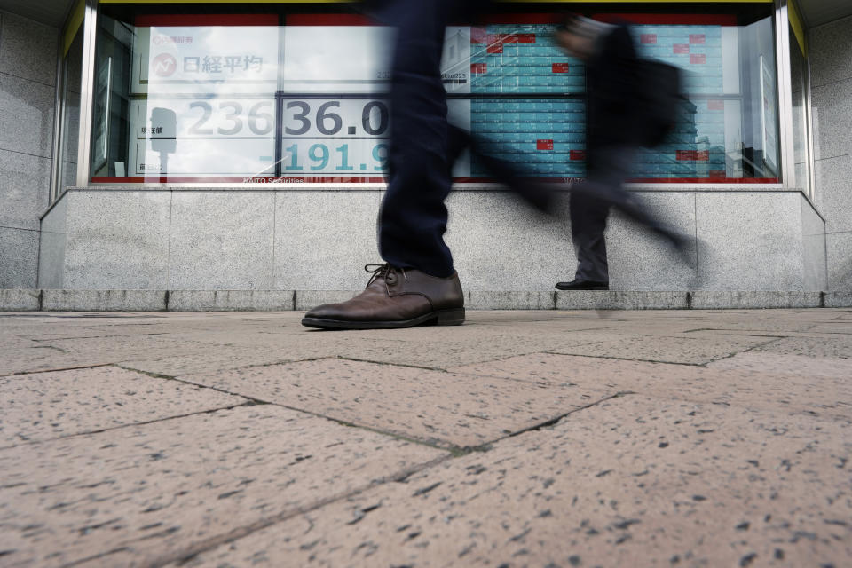 People walk past an electronic stock board showing Japan's Nikkei 225 index at a securities firm in Tokyo Monday, Feb. 10, 2020. Asian stock markets slid Monday after China reported an uptick in new cases of its virus outbreak and analysts warned optimism the disease is under control might be premature. (AP Photo/Eugene Hoshiko)