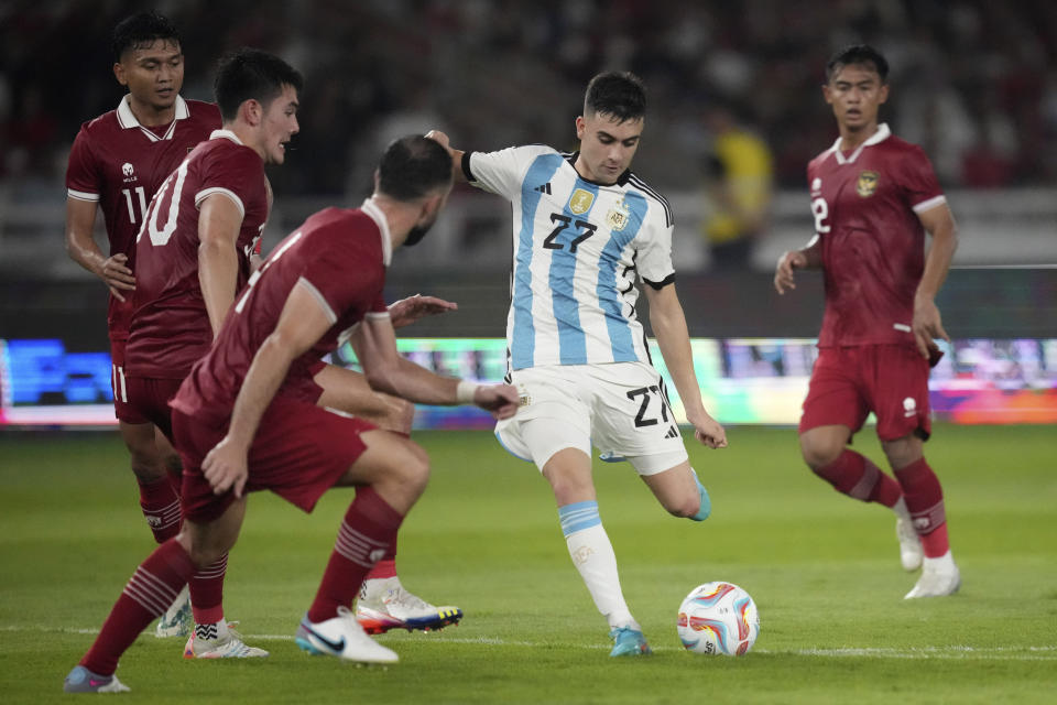 Argentina's Facundo Buonanotte, center, battles for the ball against Indonesia's Dendy Sulistiawan, from left to right, Elkan Baggott, and Jordi Amat during their friendly soccer match at Gelora Bung Karno Main Stadium in Jakarta, Indonesia, Monday, June 19, 2023. (AP Photo/Achmad Ibrahim)