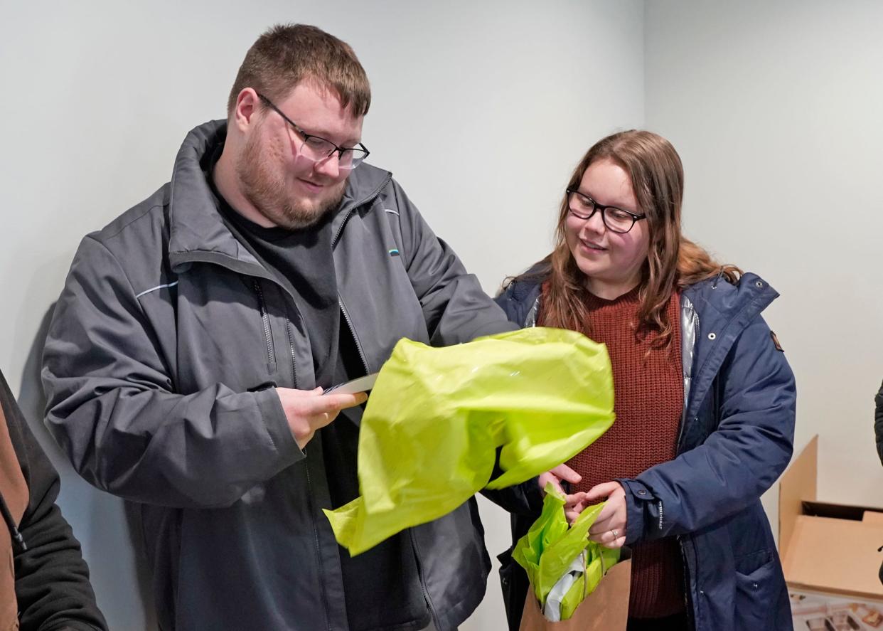 New homeowners Jacob Trentman and Hannah Phair open gifts that were gifted to them Monday, Nov. 27, 2023, during a ribbon cutting and home dedication ceremony conducted by Habitat for Humanity of Lenawee County that welcomed them to their new house in Adrian.