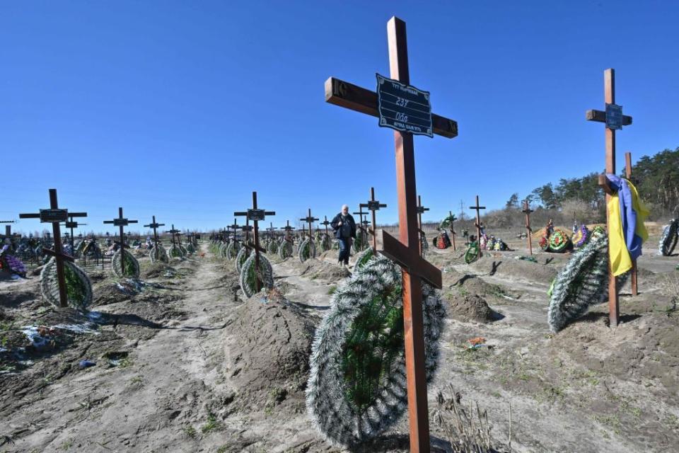 A man walks among graves of unidentified people who were killed in the Ukrainian town of Bucha, northwest of Kyiv, on March 30, 2023. Bodies of a few dozen people found in Bucha's mass grave have not been identified yet. (Photo by Sergei Supinsky/AFP via Getty Images)
