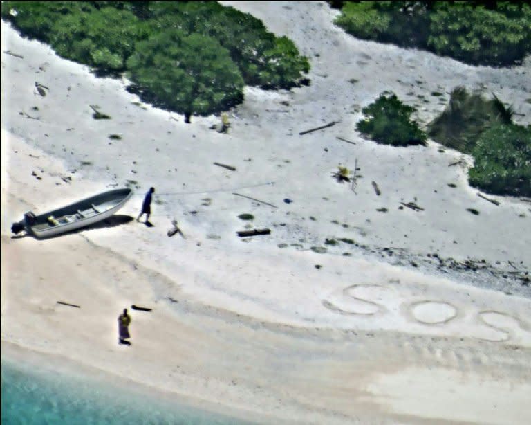 A US Navy photo shows two people signalling for help by writing