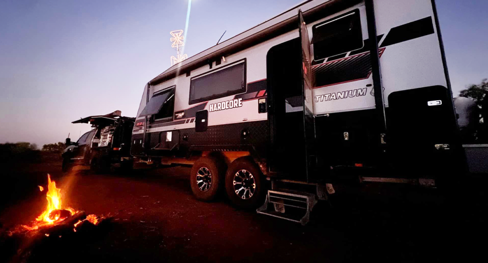 A 34-foot caravan behind a ute at a campfire. 