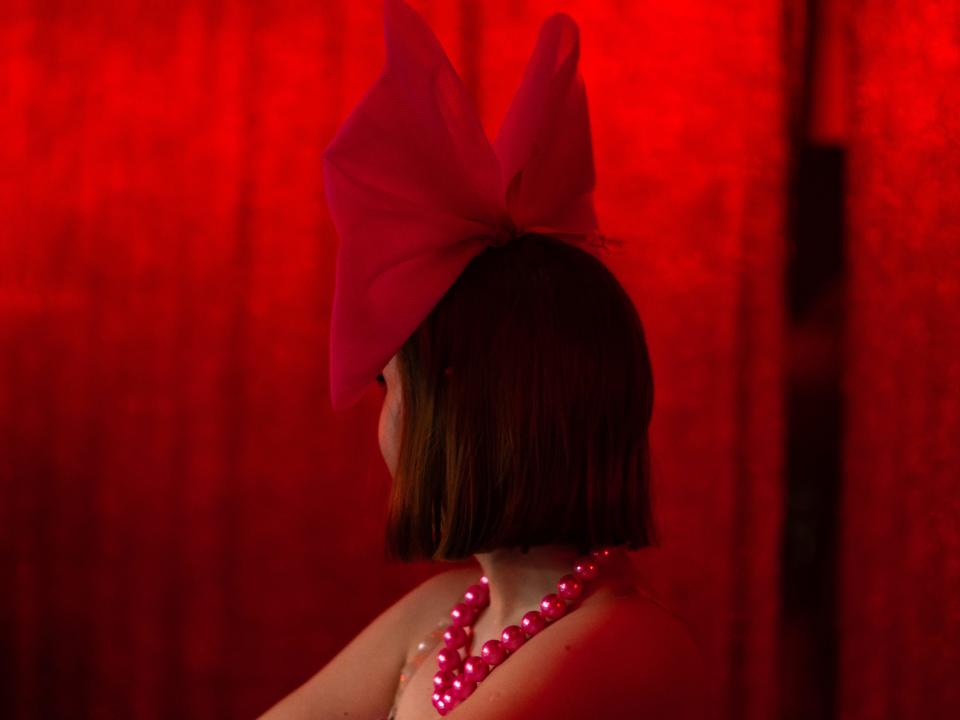 Woman wearing a big red bow with red background.